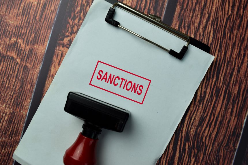 Close up Red Handle Rubber Stamper and text Sanctions isolated on White Background.