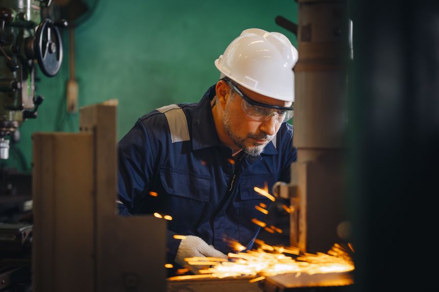 Engineer technician Hispanic Latin worker male working using Surface Grinding machine working in heavy metal industry factory