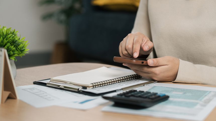 The concept of tax return preparation and financial management. Businessman calculates taxes using calculator and laptop. finance, Income tax, tax documents, and savings, File taxes online.