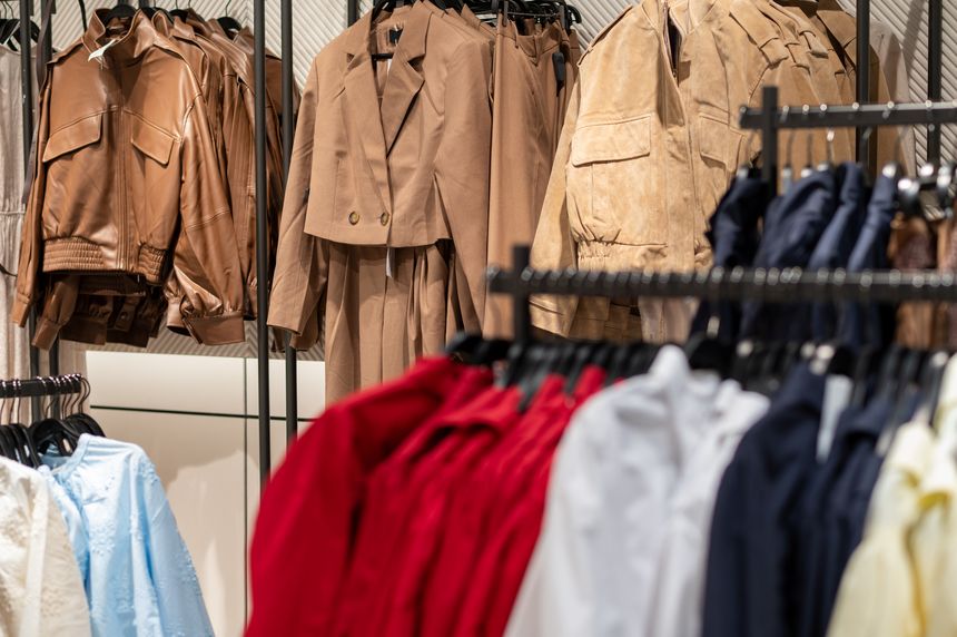 Selection of brown faux leather and suede jackets hanging on a rack in a modern clothing boutique. Fashion retail display with seasonal autumn collection on background in a shopping mall interior