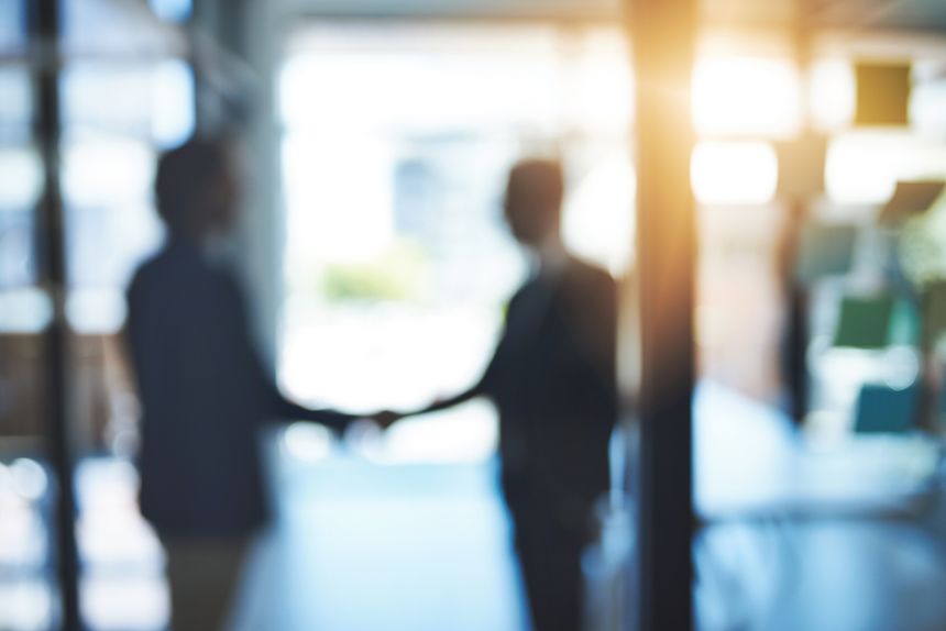 Defocused shot of two businesspeople shaking hands in an office
