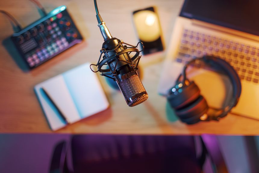 Professional audio equipment, notebook, laptop and smartphone on the desk in the home studio, microphone in the foreground, top view: content creation, livestreaming and entertainment concept