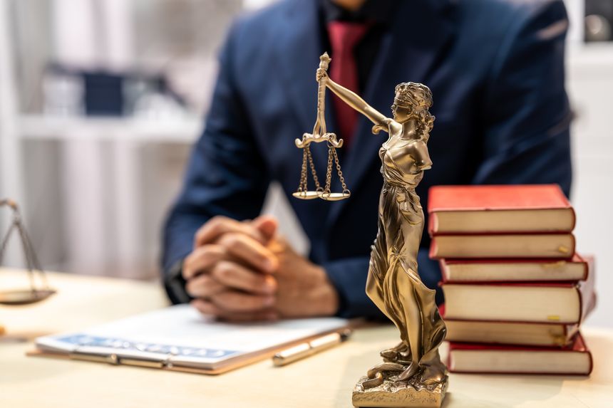 Lawyer office desk with justice statue, scales, legal books and laptop, showing professional legal advice, court concept and balanced decision making.
