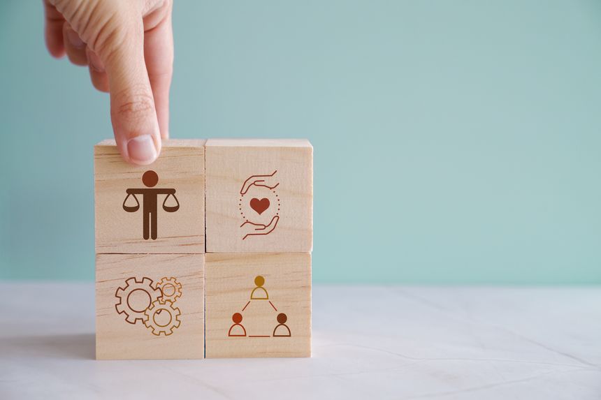 Hand holding wooden block with human scale, business ethics and corporate compliance concept