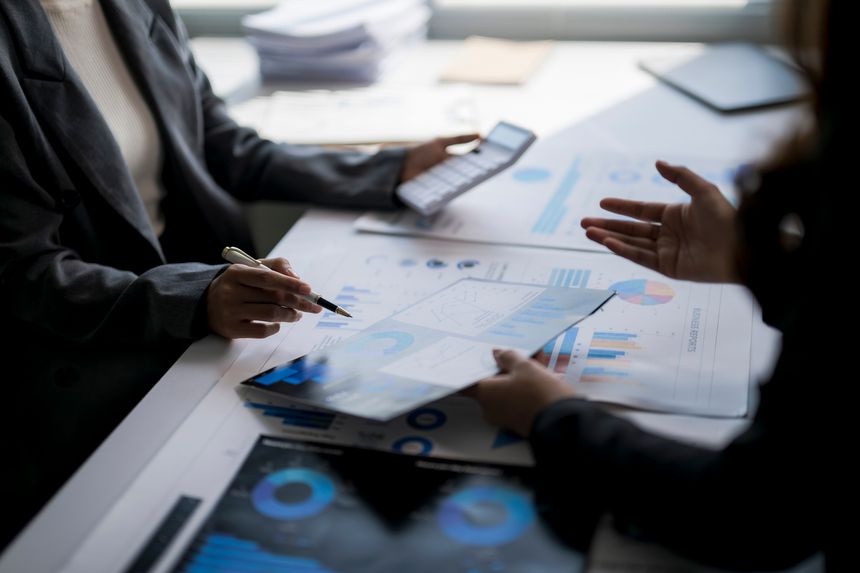 Business colleagues discussing finance charts and calculating revenue in an office setting