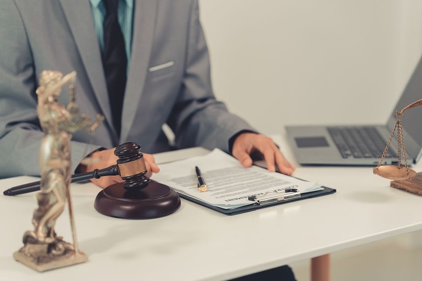 Close up of attorney hand knocking wooden gavel on sound block for judgement or authority.