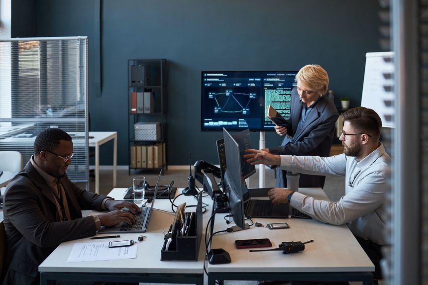 Wide shot of diverse business team reviewing data dashboards, coding, coordinating workflow in office. Suitable for corporate communication, IT management, teamwork campaigns