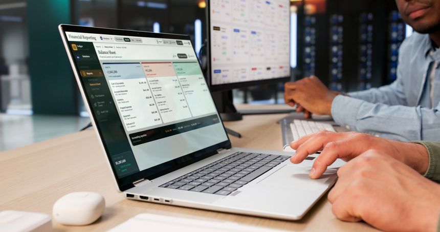 Two Business Professionals Reviewing Financial Statements Together On A Laptop.
