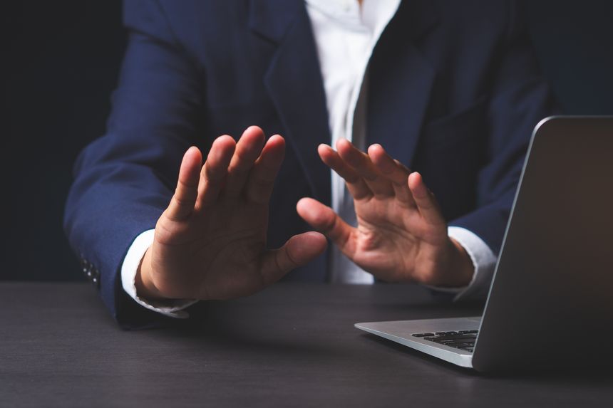 Close-up of hands making stop gesture at desk, symbolizing rejection, boundaries, and decision making in business context.