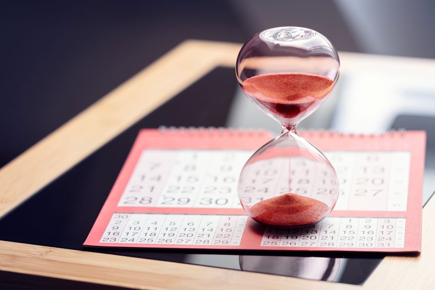 Hour glass on top of calendar concept for time slipping away for important appointment date, schedule and deadline